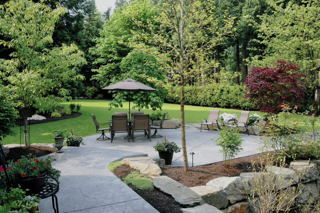 Landscape view of a beautiful outdoor living area including a large yard beyond the pavement