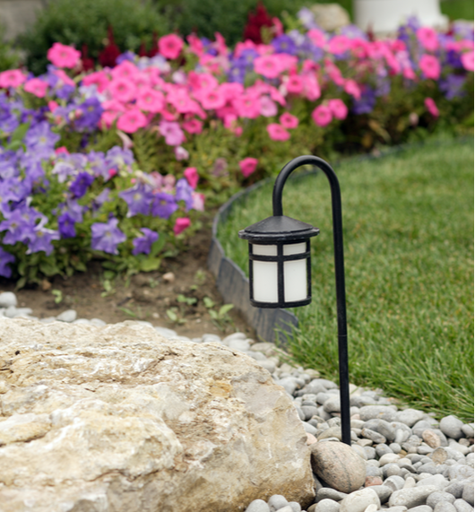 Small outdoor lamp lighting the barrier between the flower bed and the lawn