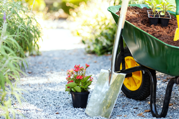 Wheelbarrow and shovel on a gravel path for planting flowers